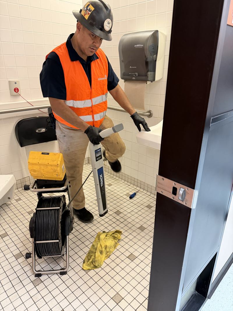 GarSan technician in high visibility gear clearing a main line with a drain machine